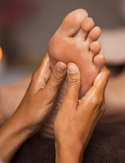 Reflexologist applying pressure to feet during treatment